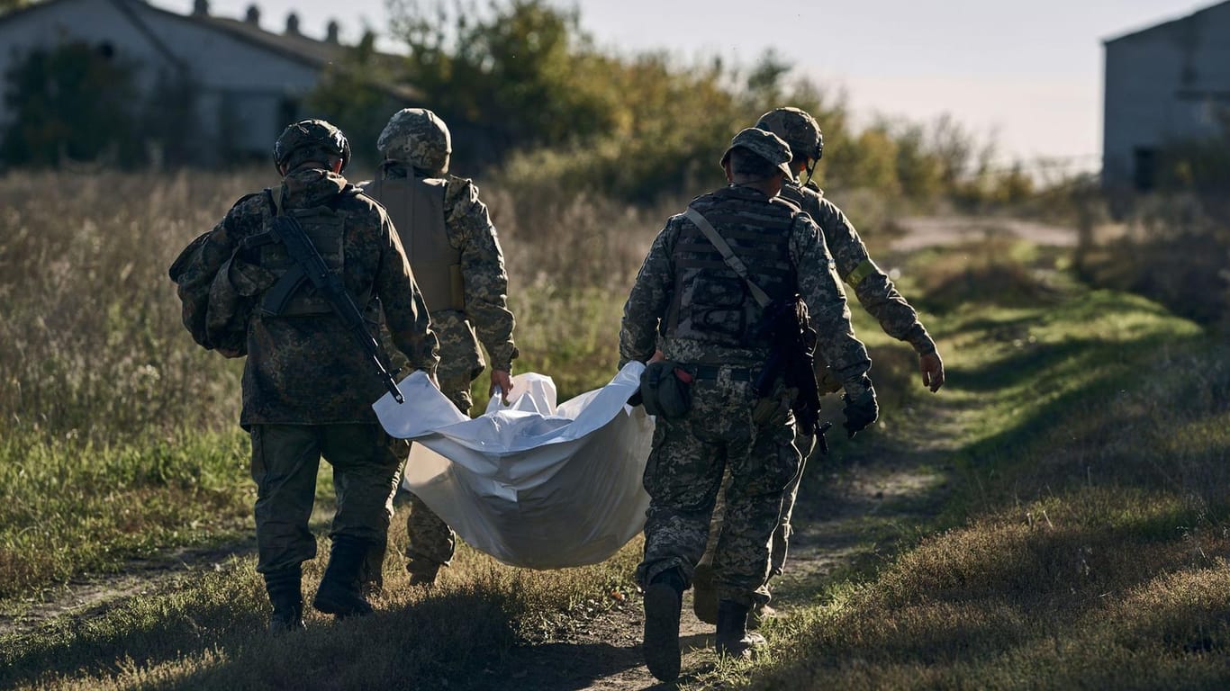 Ukrainische Soldaten tragen einen Toten weg.