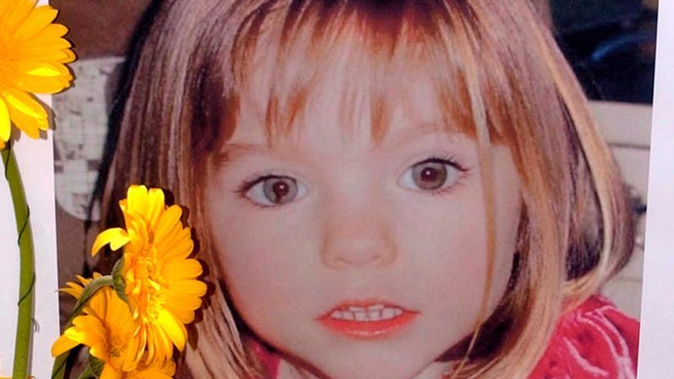 Blumen stehen vor einem Bild, das die verschwundene Madeleine McCann (Maddie) zeigt: Der Verdächtige wurde nun in fünf anderen Fällen angeklagt.
