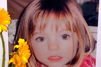 Blumen stehen vor einem Bild, das die verschwundene Madeleine McCann (Maddie) zeigt: Der Verdächtige wurde nun in fünf anderen Fällen angeklagt.