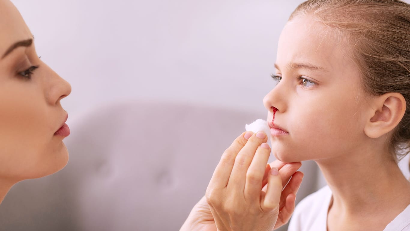 Frau behandelt Kind mit blutender Nase