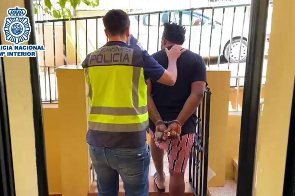 Spanische Polizeibeamte führen einen Verdächtigen ab.