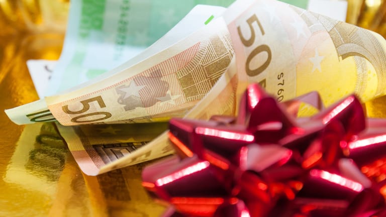 Euroscheine mit Geschenkband (Symbolbild): Weihnachtsgeld versüßt Arbeitnehmern das Jahresende.