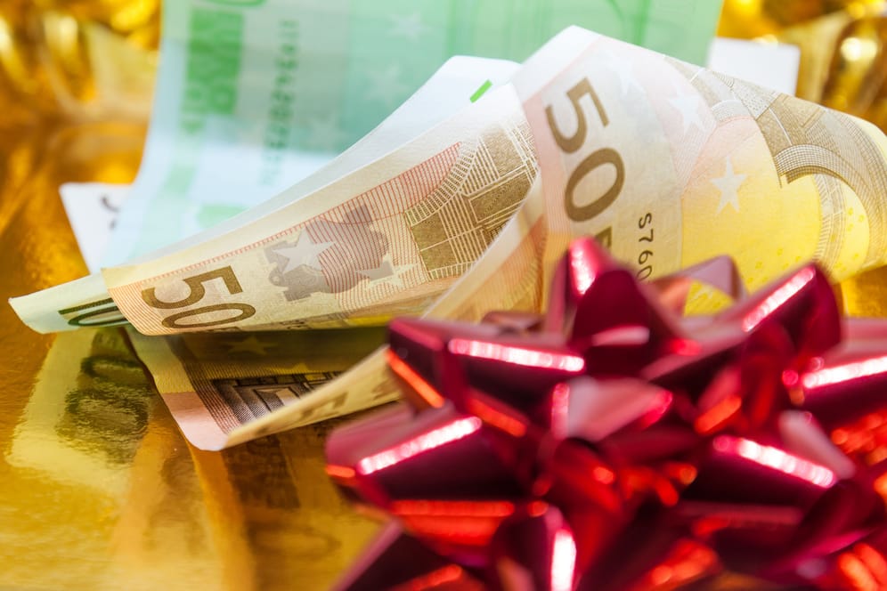 Euroscheine mit Geschenkband (Symbolbild): Weihnachtsgeld versüßt Arbeitnehmern das Jahresende.