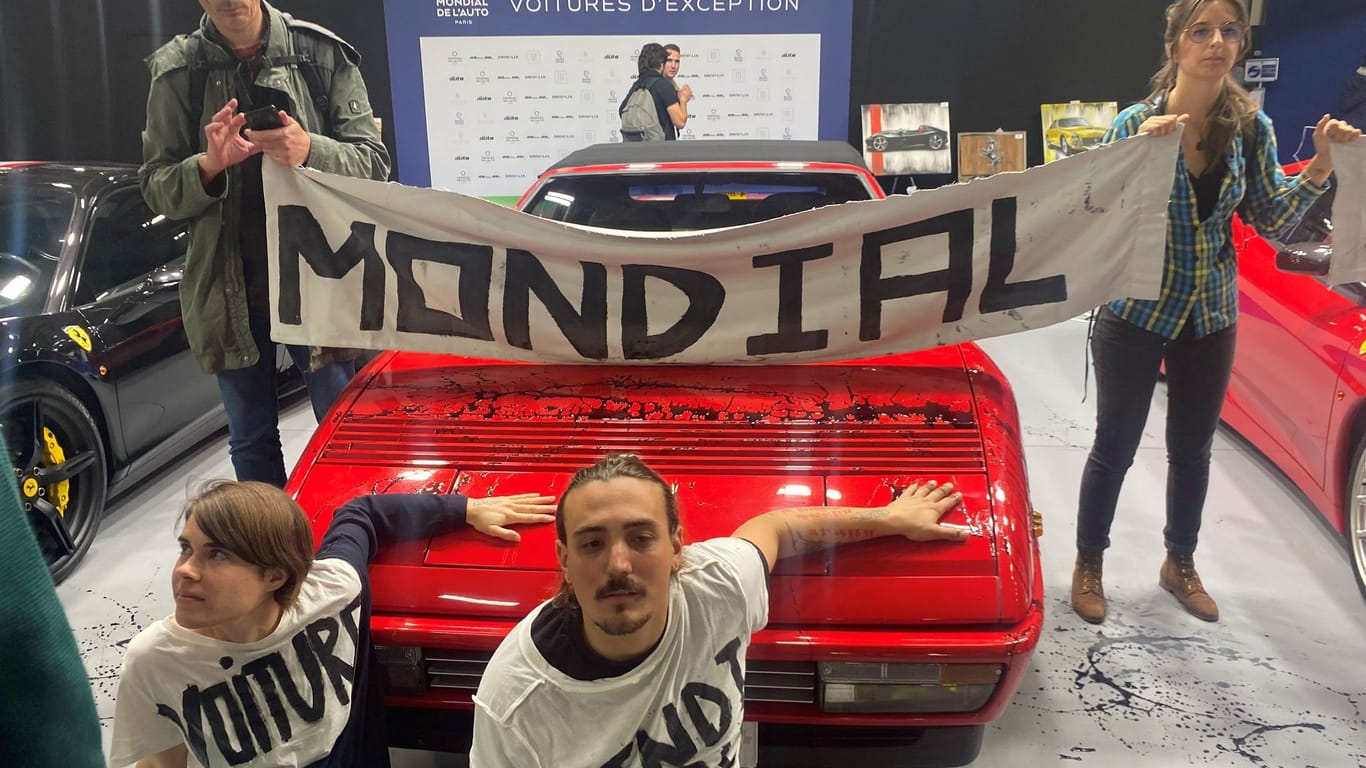 Klimaaktivisten kleben sich an einem Sportwagen auf der Pariser Automesse fest.