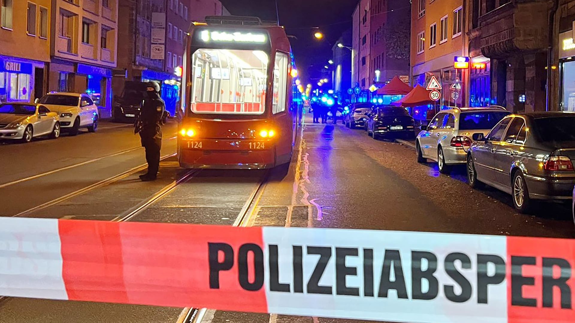 Ein Polizist steht mit einer Maschinenpistole neben einer Straßenbahn hinter einer Polizeiabsperrung: Gegen 20 Uhr hat es eine gewaltsame Auseinandersetzung zwischen mehreren Personen gegeben.