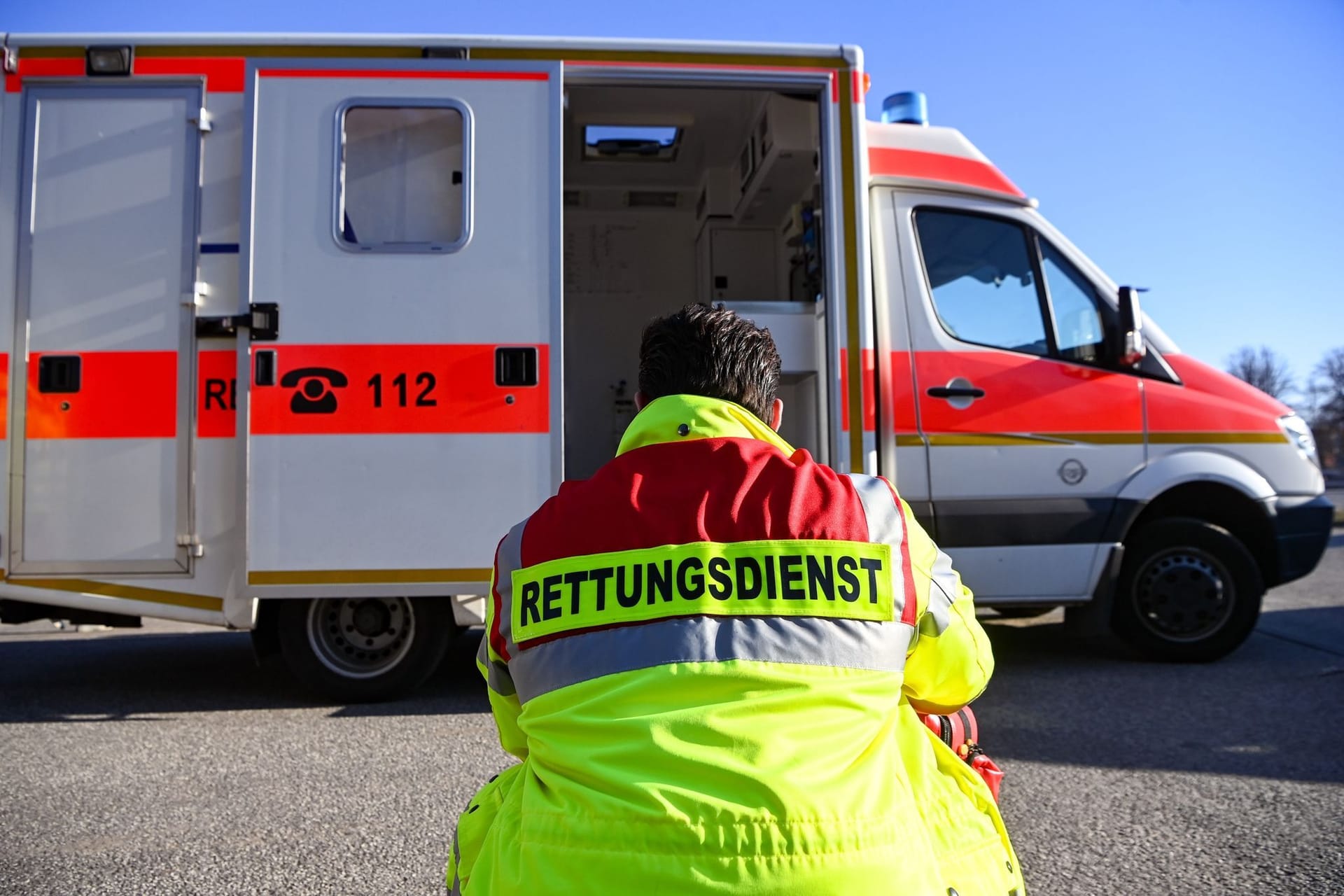 "Rettungsdienst" steht auf der Jacke eines Mannes vor einem Rettungswagen (Symbolbild): Nur zufällig waren die Rettungskräfte vor Ort.