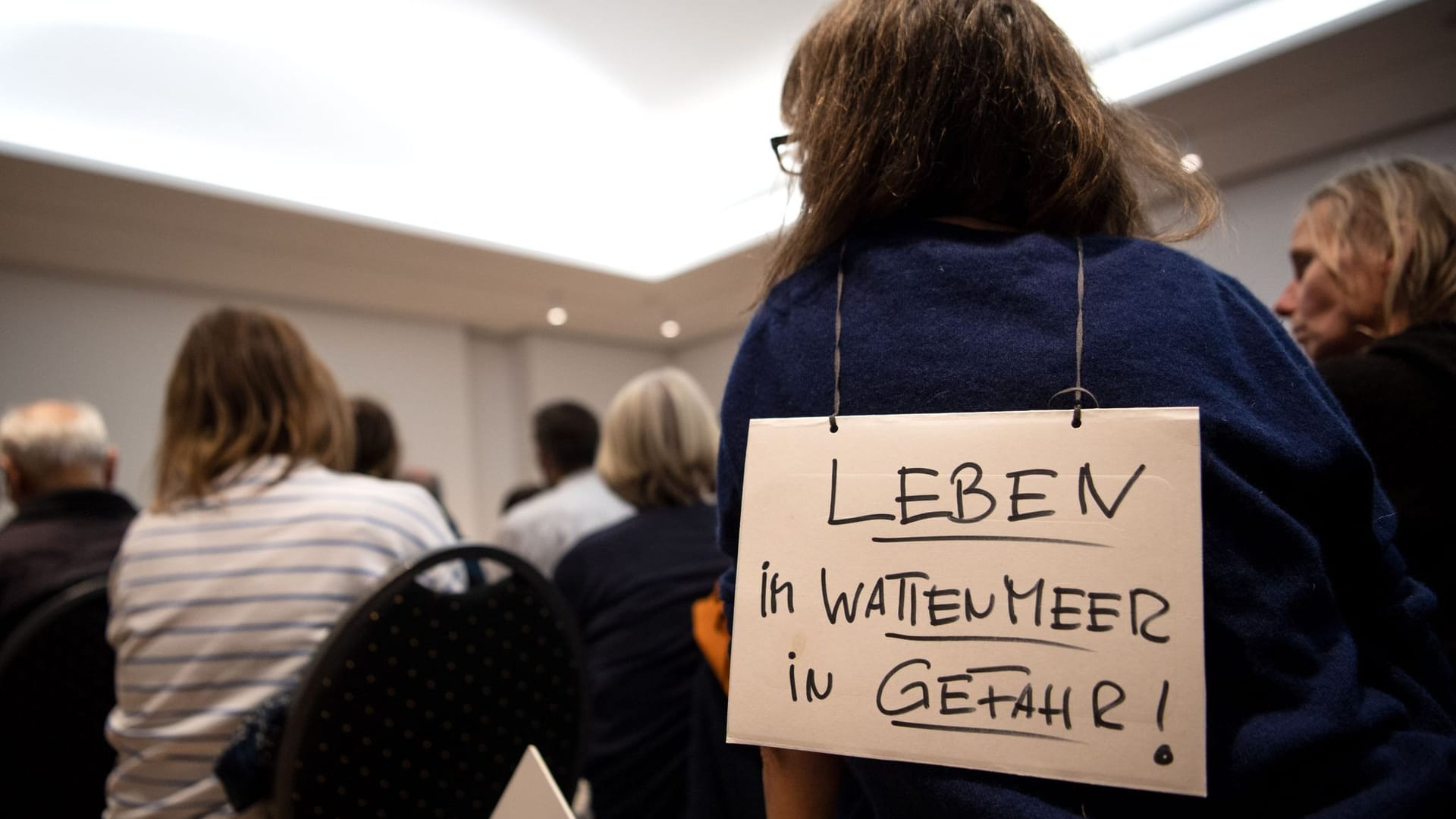 "Leben im Wattenmeer in Gefahr" steht auf einem Plakat einer Teilnehmerin bei der Informationsveranstaltung des Umweltministeriums zum LNG-Terminal.