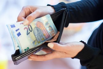 Eine Frau zieht Geldscheine aus dem Portemonnaie (Symbolbild): Die Mehrzahl der Deutschen erwartet in Zukunft einen finanziellen Engpass.