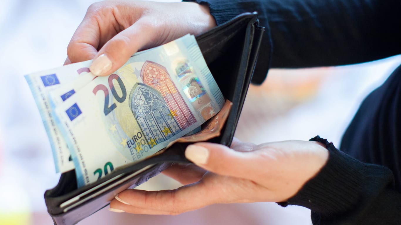 Eine Frau zieht Geldscheine aus dem Portemonnaie (Symbolbild): Die Mehrzahl der Deutschen erwartet in Zukunft einen finanziellen Engpass.
