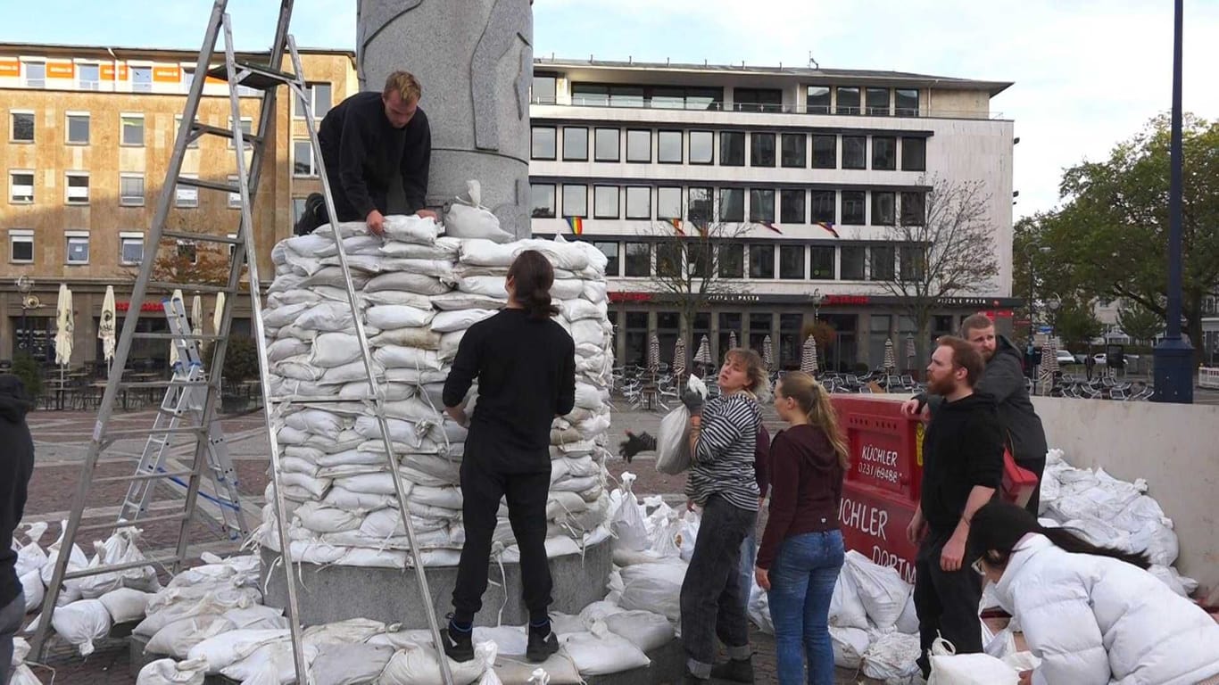 Zusammen mit Medienkünstler und Dozent der FH-Dortmund, Achim Mohné, stapelten die Studierenden die 15 Kilo schweren Säcke um die Friedenssäule.