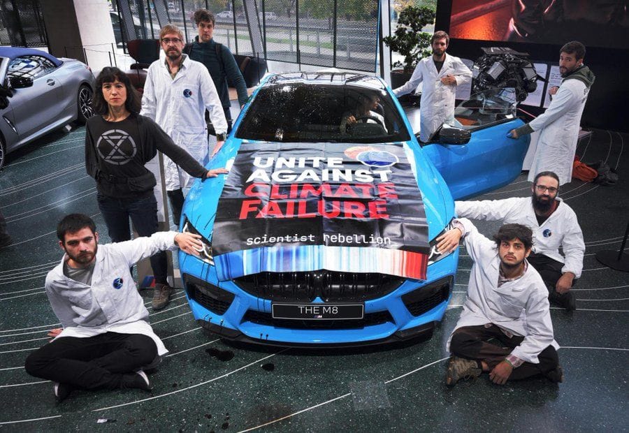 Aktivisten der Protestgruppe "Scientist Rebellion" kleben an einem Austellungs-Auto in der BMW-Welt in München.
