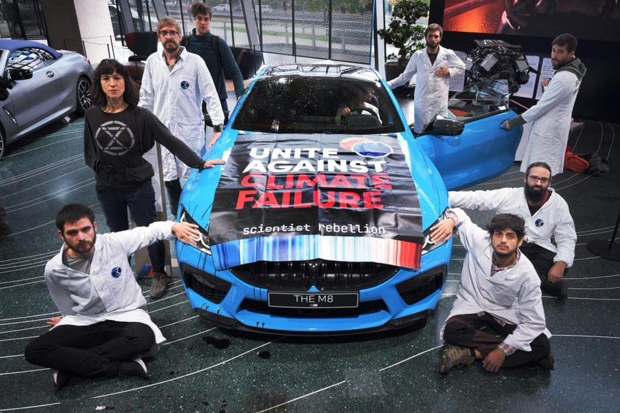 Aktivisten der Protestgruppe "Scientist Rebellion" kleben an einem Austellungs-Auto in der BMW-Welt in München.