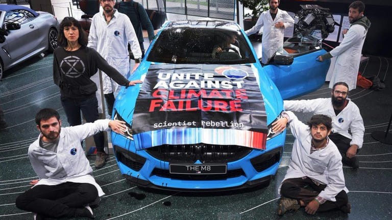 Aktivisten der Protestgruppe "Scientist Rebellion" kleben an einem Austellungs-Auto in der BMW-Welt in München.