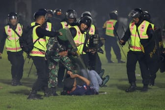 SicherheitFootball gamee halten einen Zuschauer am Boden: Bei Ausschreitungen nach einem Fußballspiel in Indonesien gab es 127 Tote.