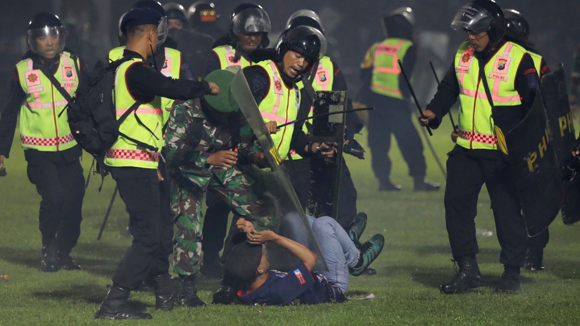 SicherheitFootball gamee halten einen Zuschauer am Boden: Bei Ausschreitungen nach einem Fußballspiel in Indonesien gab es 127 Tote.