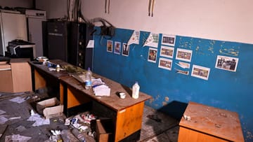 Advertising posters on the wall, documents scattered on the floor.