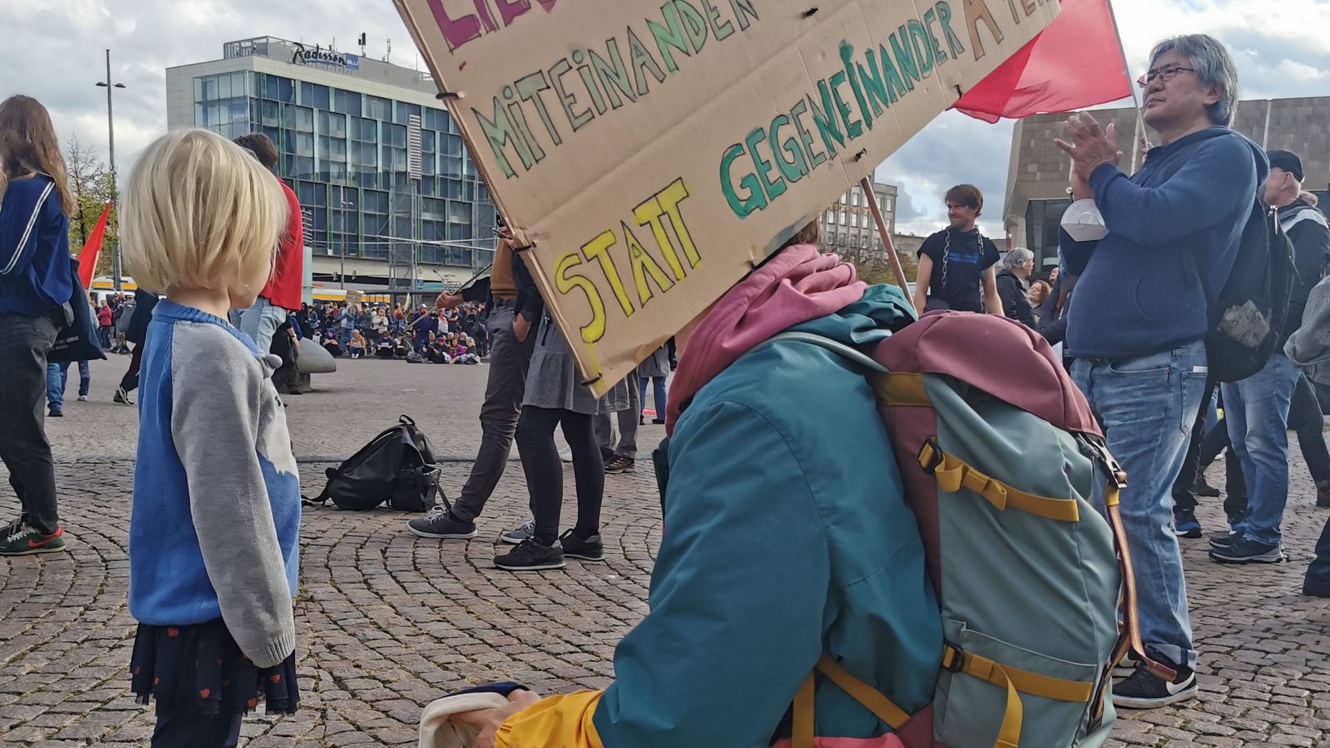 Felix hat ein Schild und seinen Sohn zur Demonstration in Leipzig mitgebracht. Bei ihnen wird das Geld knapp.