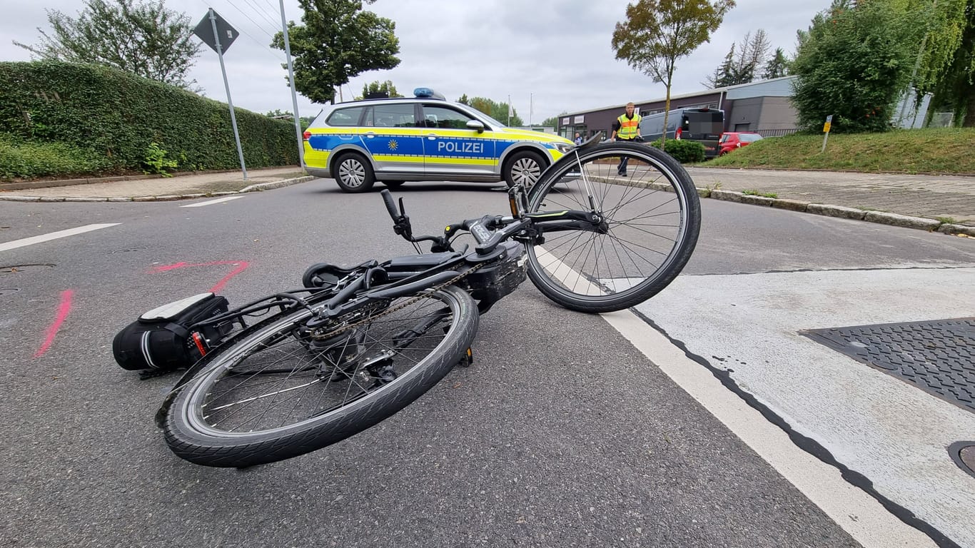 Ein Fahrrad liegt vor einem Polizeiwagen auf der Straße (Symbolbild): Alle vier Radfahrer mussten in Krankenhäuser gebracht werden.