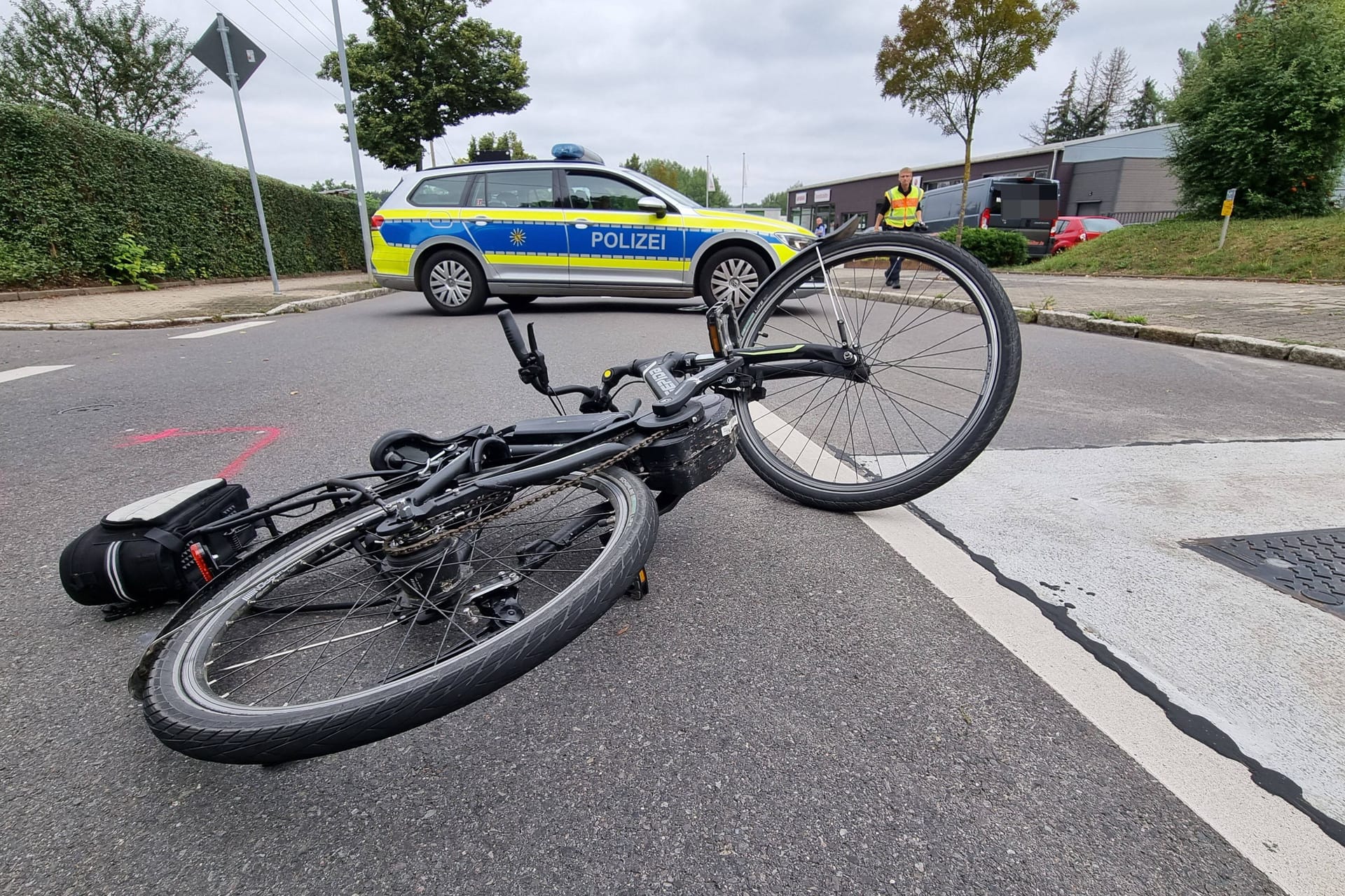 Ein Fahrrad liegt vor einem Polizeiwagen auf der Straße (Symbolbild): Alle vier Radfahrer mussten in Krankenhäuser gebracht werden.