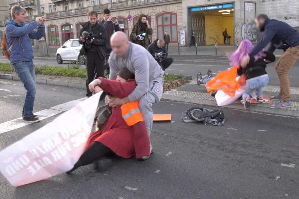 Klimaaktivistinnen blockieren am Frankfurter Tor (Archivbild): Männer zerren die Frauen von der Straße.