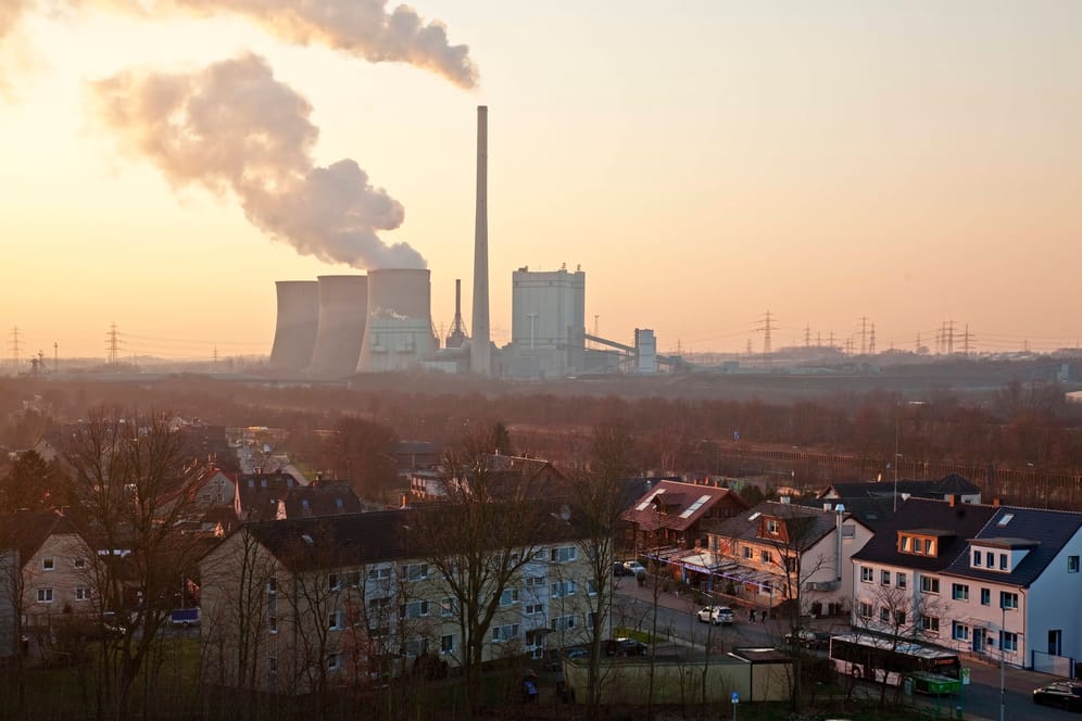 Wohnsiedlung mit Kraftwerk im Hintergrund (Symbolbild): Grundversorger sind jene Energieunternehmen, die die meisten Haushalte in einem Netzgebiet beliefern.