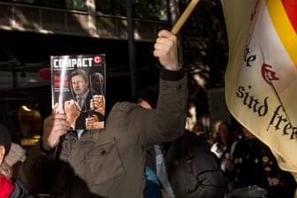 Demonstrationsteilnehmer der "Querdenken"-Demo in Hannover: Ein Mann verdeckt sein Gesicht – mit dem rechtsextremen "Compact"-Magazin.