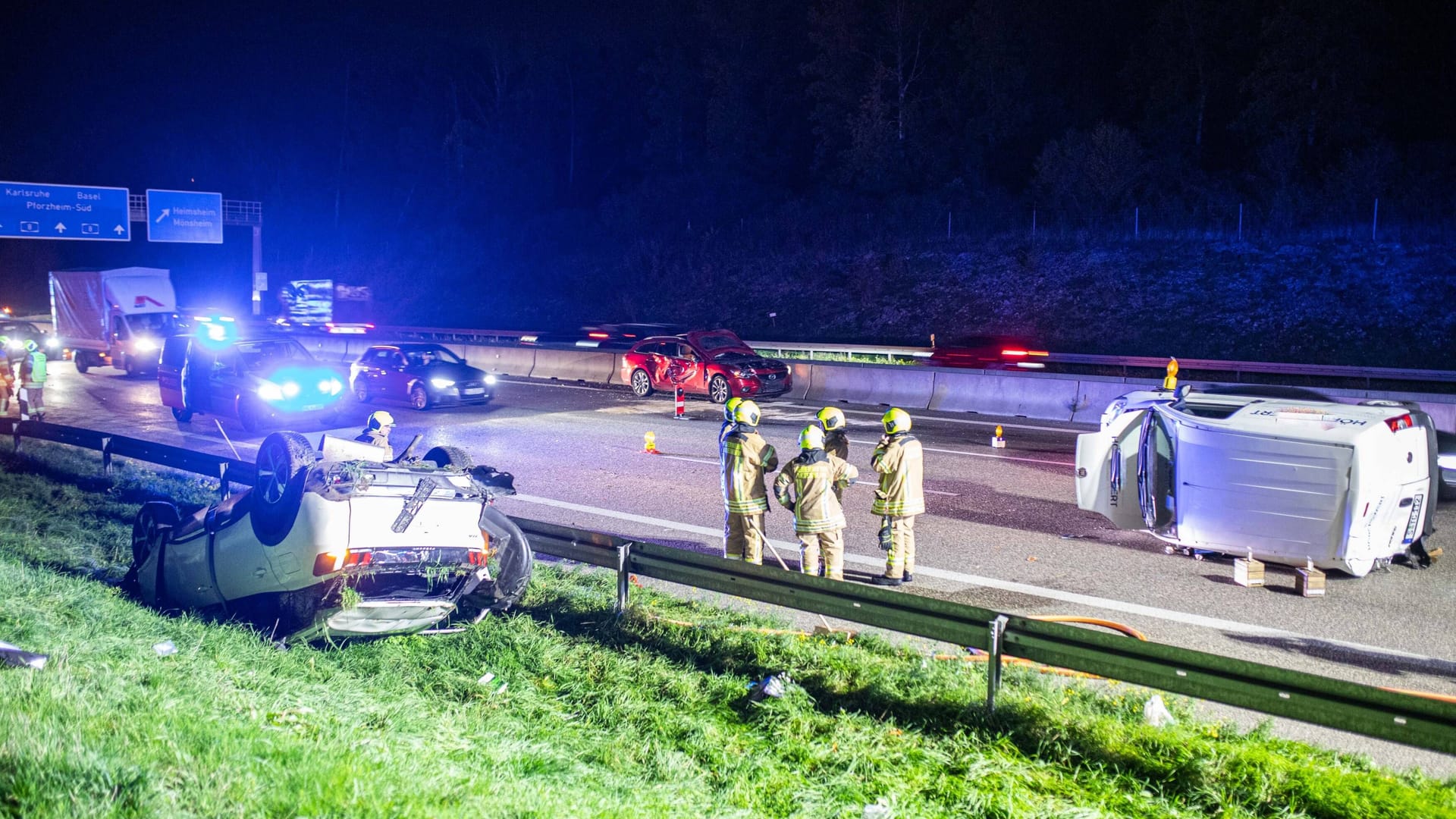 Einsatzkräfte am Unfallort zwischen zwei Fahrzeugen: Ein Peugeot liegt auf dem Dach (links) und ein Fiat auf der Seite (rechts).