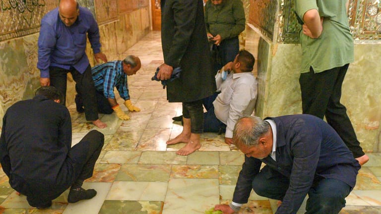 Mitarbeiter der Pilgerstätte im Iran reinigen den Ort nach dem Anschlag,