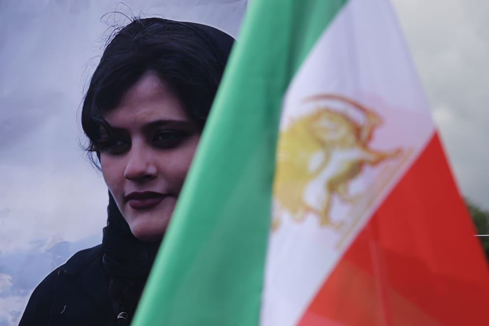 Bild der getöteten Mahsa Jina Amini hinter der iranischen Flagge: Weltweit solidarisieren sich Menschen mit den feministischen Protesten im Iran.