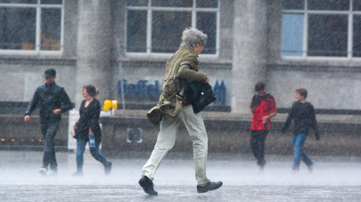 Ein Mann rennt in Köln durch den Regen (Symbolbild): In den nächsten Tagen soll es in NRW regnerisch bleiben.