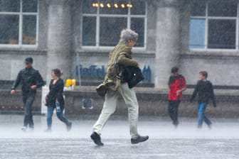 Ein Mann rennt in Köln durch den Regen (Symbolbild): In den nächsten Tagen soll es in NRW regnerisch bleiben.