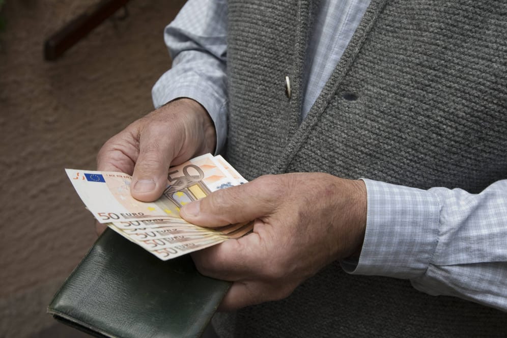 Ein älterer Mann hält Bargeld in den Händen (Symbolbild): Ein Senior aus Oppenweiler wurde um 88.000 Euro betrogen.