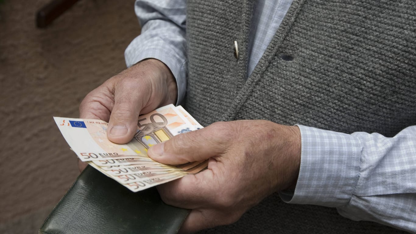 Ein älterer Mann hält Bargeld in den Händen (Symbolbild): Ein Senior aus Oppenweiler wurde um 88.000 Euro betrogen.