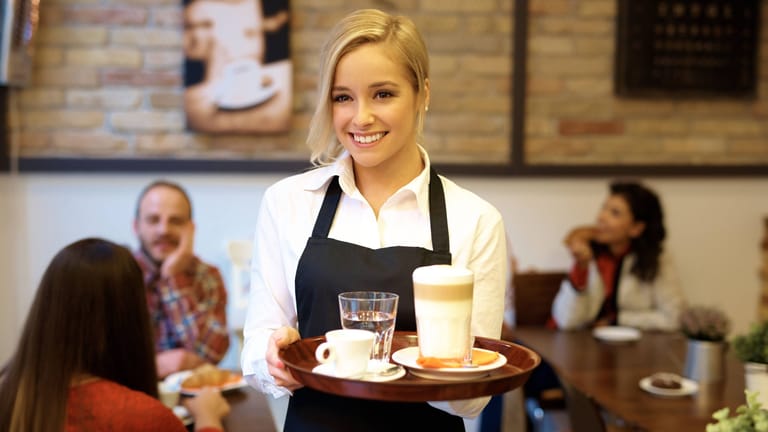 Eine Kellnerin serviert Getränke (Symbolfoto): Eintritt wollen manche Wirte die Energiepauschale nicht nennen.