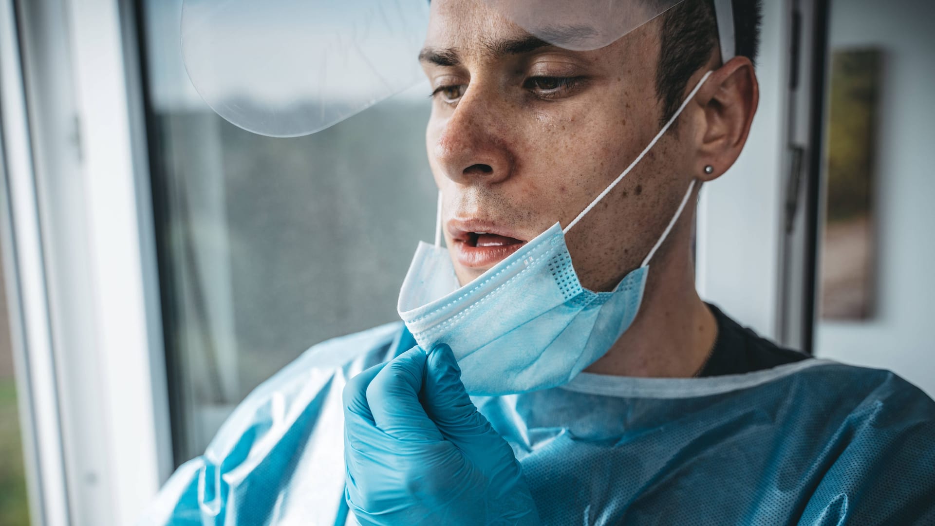 Eine Pflegekraft zieht erschöpft die Maske aus (Archivbild): Die Belastung für das Berliner Gesundheitssystem ist hoch.