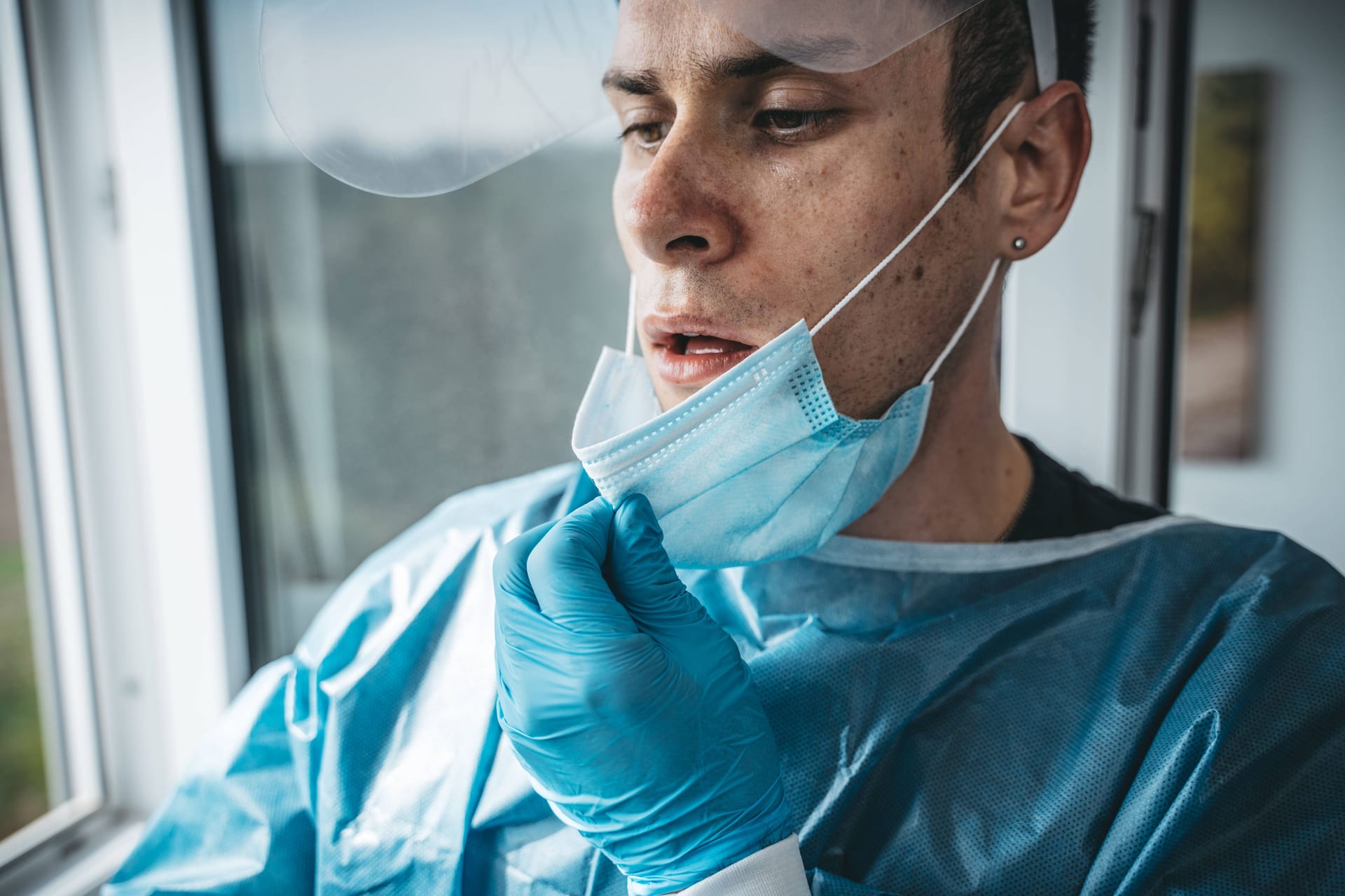 Eine Pflegekraft zieht erschöpft die Maske aus (Archivbild): Die Belastung für das Berliner Gesundheitssystem ist hoch.