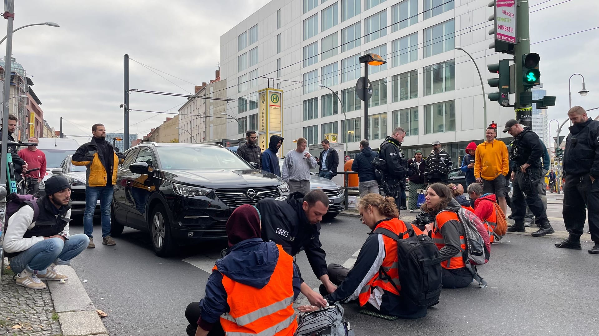 Ein Polizist löst festgeklebte Aktivisten in Berlin von der Straße ab (Archivbild): Rund eine halbe Stunde Zeitverzögerung gibt es aktuell.