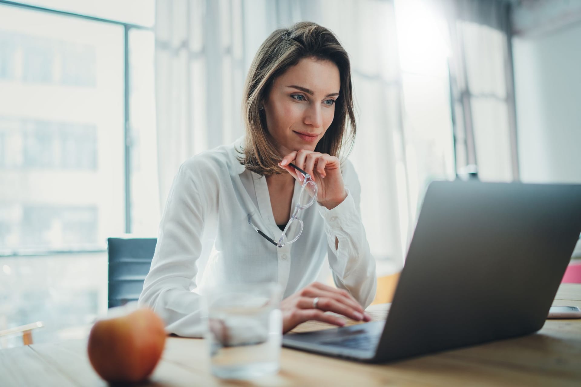 Junge Frau am Laptop (Symbolbild): In Aktien-ETFs können auch Anfänger bequem von zu Hause investieren.