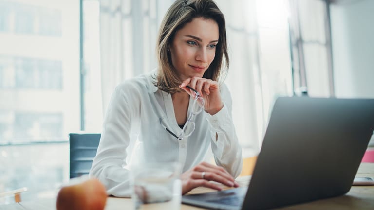 Junge Frau am Laptop (Symbolbild): In Aktien-ETFs können auch Anfänger bequem von zu Hause investieren.