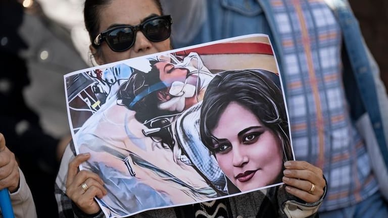 Eine Iranerin beteiligt sich in Frankfurt an einer Demonstration gegen das politische Regime im Iran. Dabei hält sie ein Plakat mit dem Bild der 22-jährigen Mahsa Amini in den Händen.
