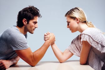 Junges Paar beim Armdrücken (Symbolbild): Kleine Angewohnheiten können zeigen, wer wo in einer Beziehung das Sagen hat.