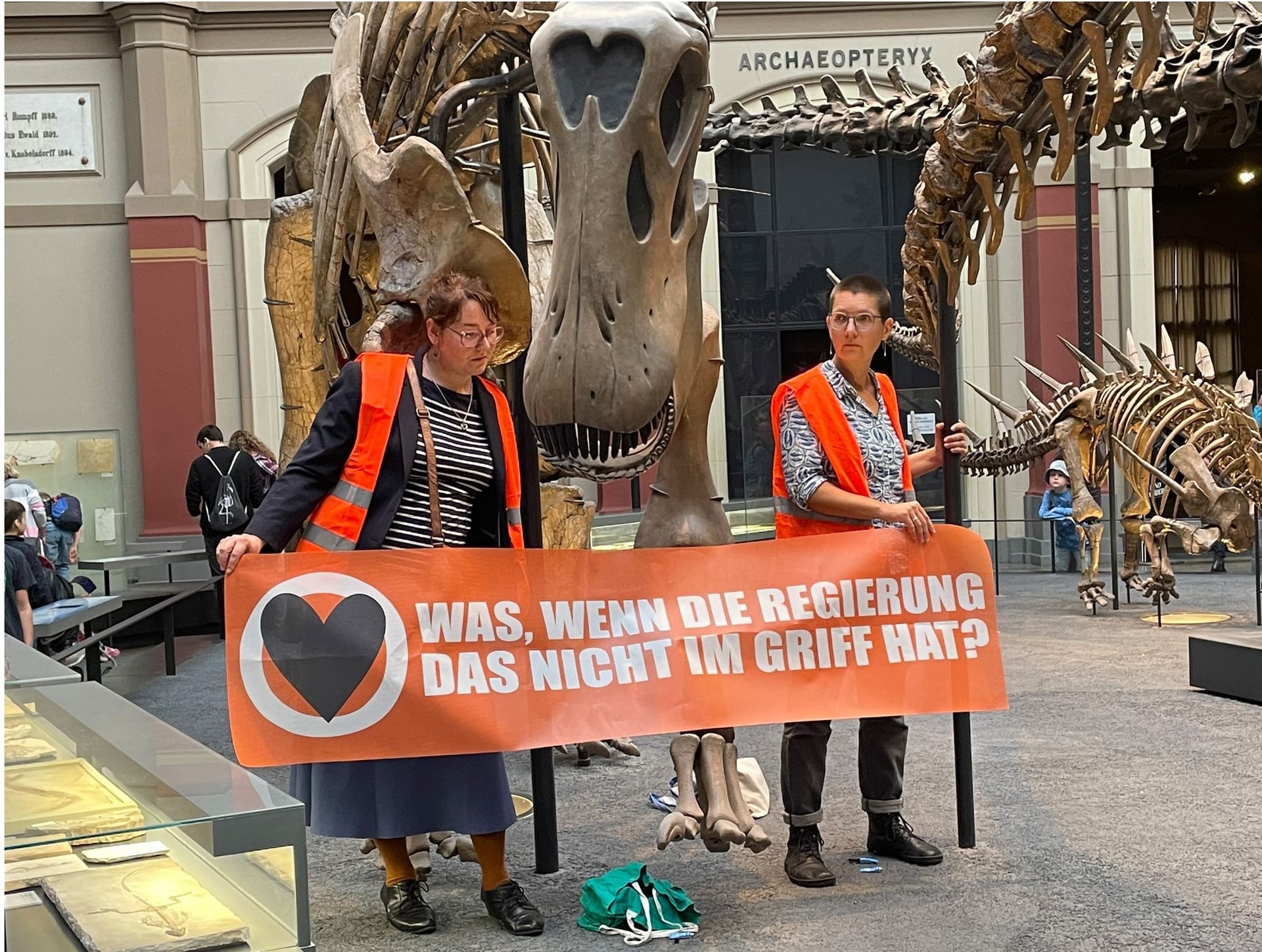 Zwei Klimaaktivistinnen im Naturkundemuseum: Auf ihrem Banner steht: "Was, wenn die Regierung das nicht im Griff hat?"
