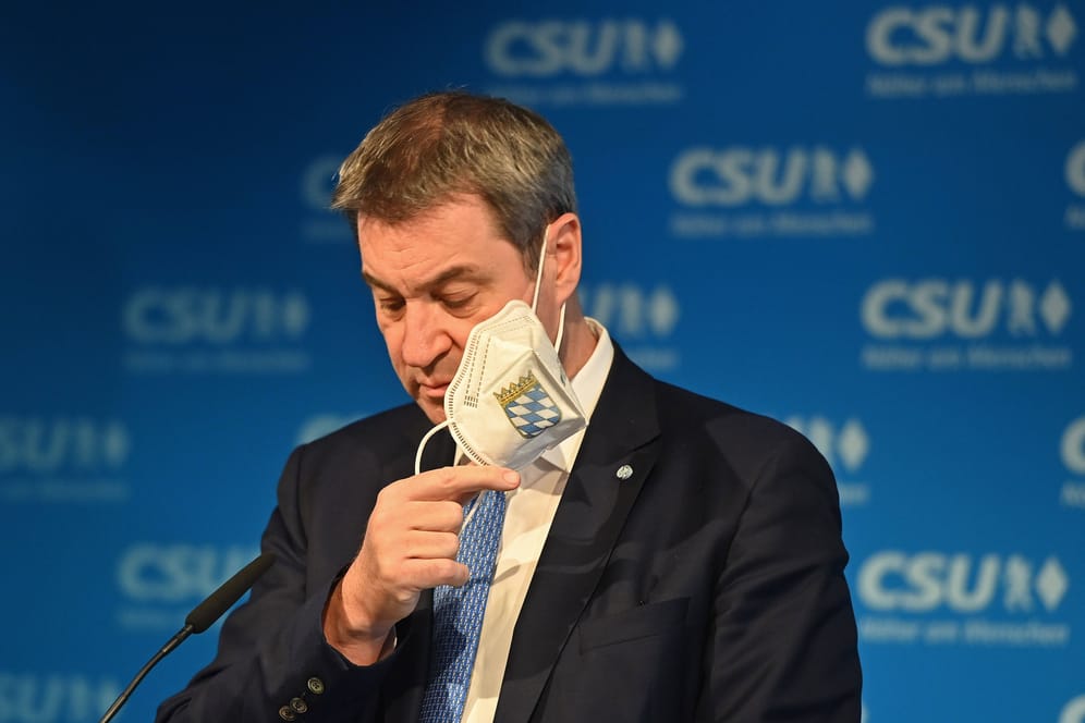 Markus Söder zieht seine FFP2-Maske bei einer Pressekonferenz aus (Archivbild): Nun denkt der Ministerpräsident laut über ein Ende der Maskenpflicht im Nahverkehr nach.