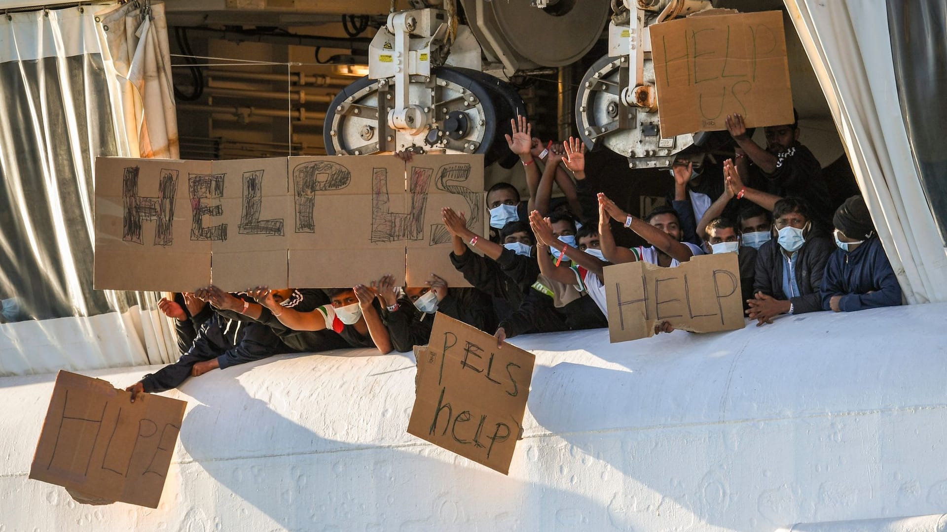 Migranten halten Transparente mit der Bitte um Hilfe an Deck des Schiffes "Geo Barents": Das Schiff durfte am Sonntag einige Menschen von Bord lassen.