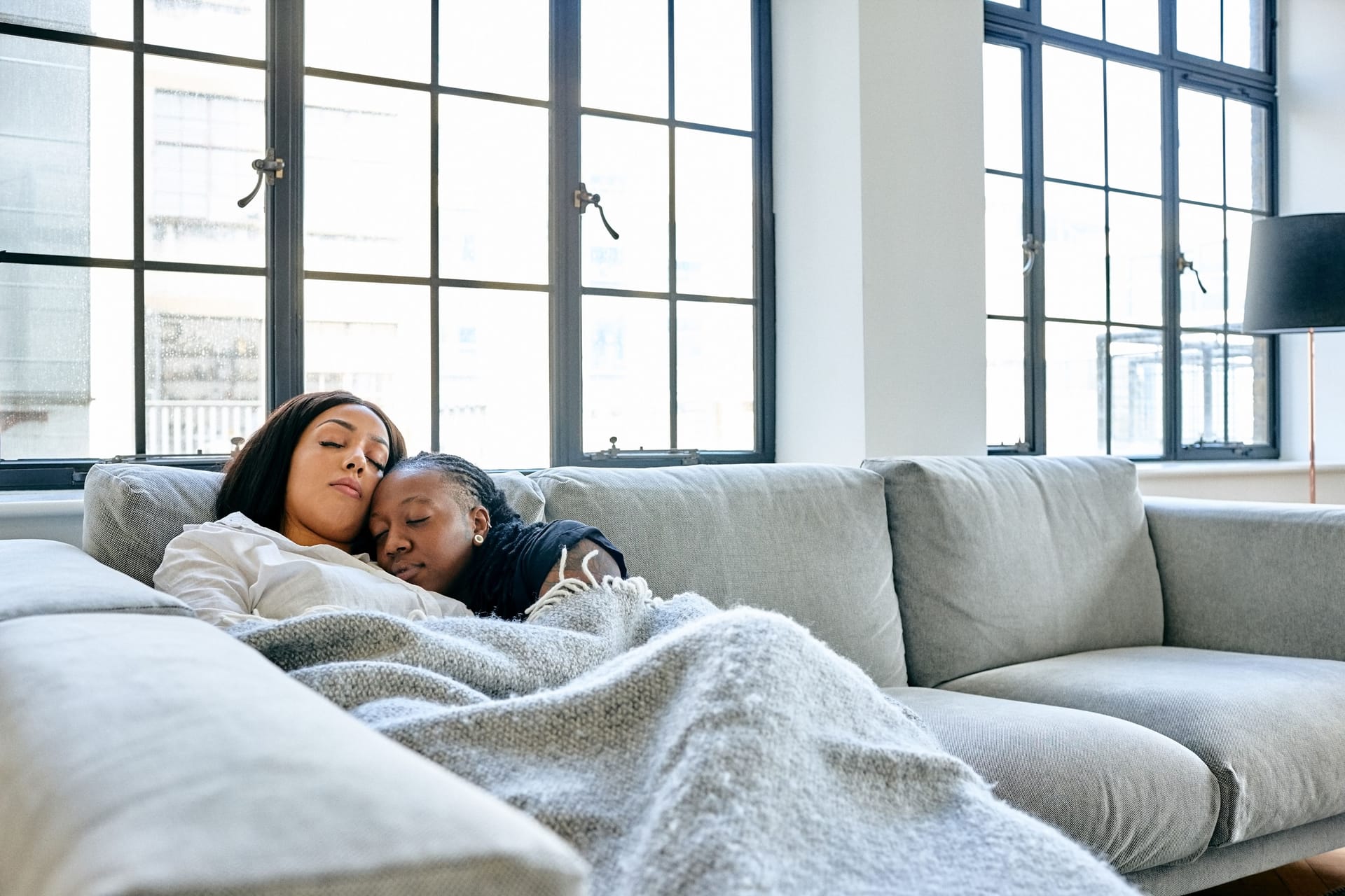 Zwei Frauen kuscheln auf dem Sofa miteinander.