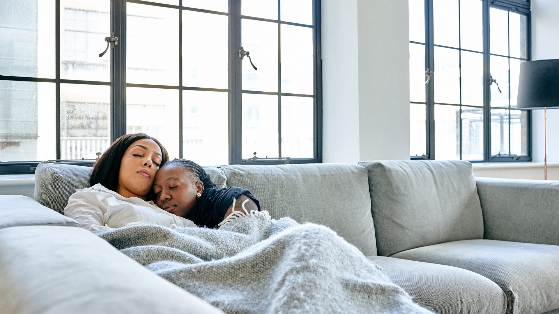 Zwei Frauen kuscheln auf dem Sofa miteinander.