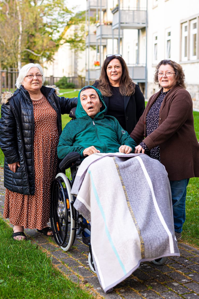 Hakan Bicici umgeben von Mutter Fatma Bicici (l), Tante Hülya Häseler (M) und Tante Hatice Moormann (r) in seinem Rollstuhl.