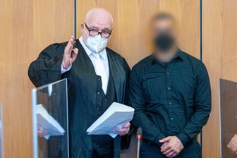 Der Angeklagte (r) steht bei Prozessauftakt neben seinem Verteidiger Matthias Waldraff in einem Saal vom Landgericht Hildesheim.