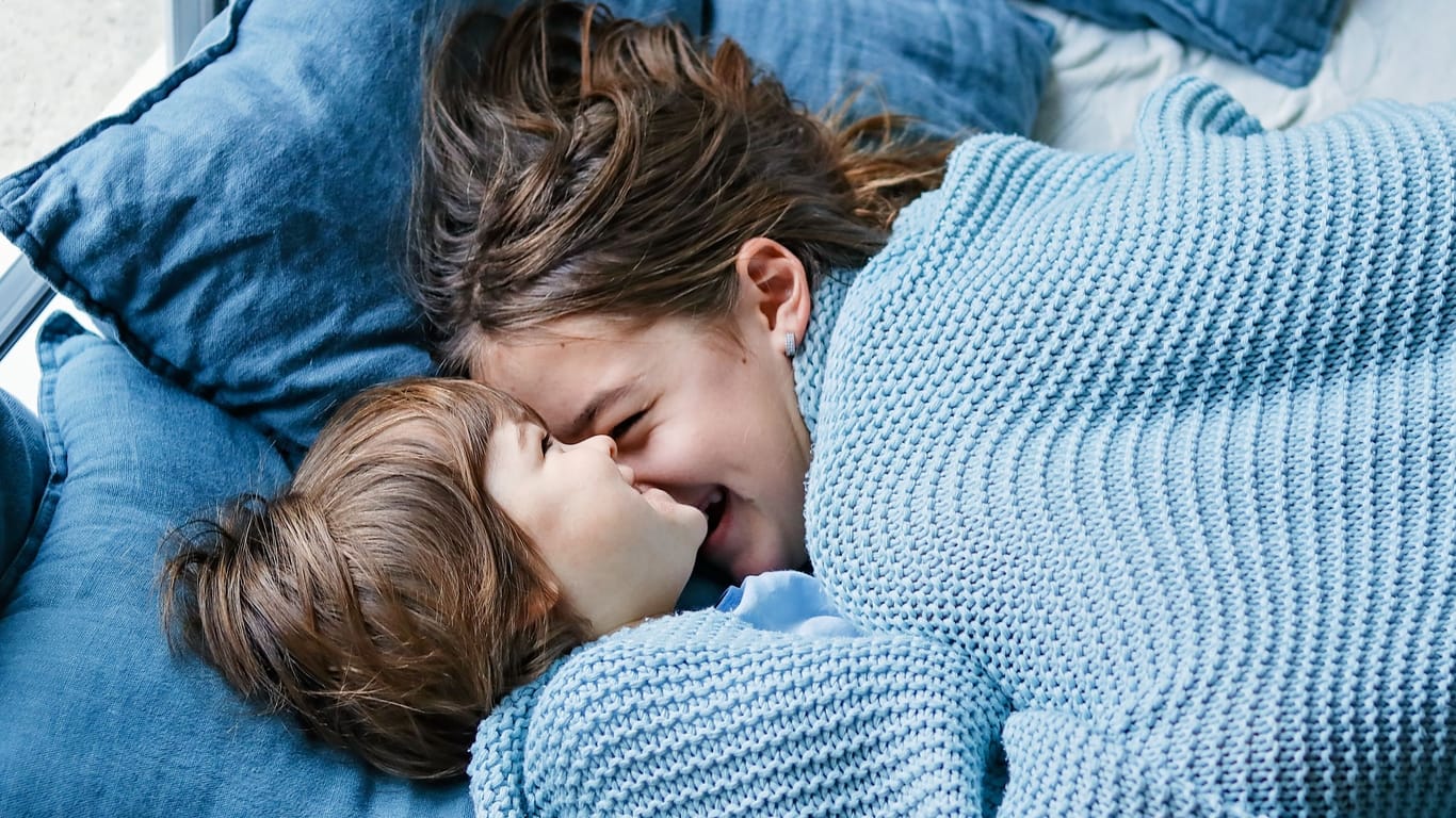 Zwei Kinder kuscheln im Bett miteinander
