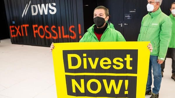 Eine Demonstrantin mit einem Schild bei einer Protestaktion im Eingangsbereich des Gebäudes der Deutsche-Bank-Fondstochter DWS in Frankfurt.